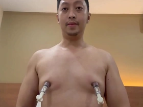 A handsome man with a slim and white skin uses nipple pumps to enhance his sexual performance.