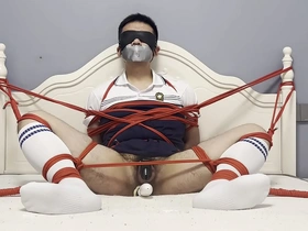 Young Asian man tied up and toyed with a dildo while struggling.