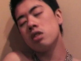 A young Asian man undresses on the beach.