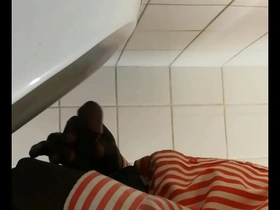 Black gay man pleasuring himself in a public restroom urinal stall.